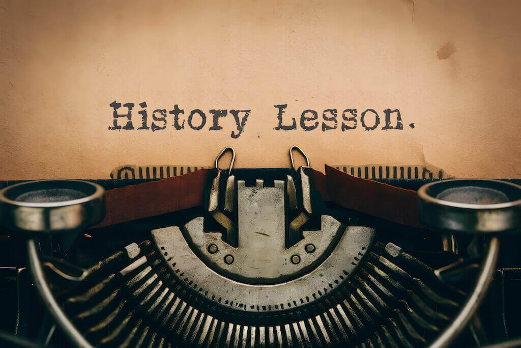 Lekcja historii webinarów – od maszyn do pisania po cyfrową edukację Zbliżenie na starą maszynę do pisania z kartką papieru i napisem „History Lesson” – symbol ewolucji technologii edukacyjnych od przeszłości do współczesnych webinarów