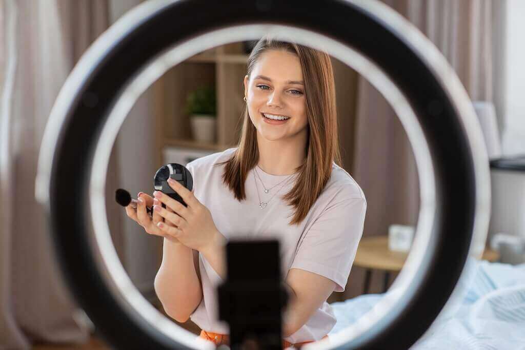 Jak wygląda webinar z lampą pierścieniową Kobieta z kosmetykami nagrywa webinar z użyciem oświetlenie lampy pierścieniowej dla webinarów