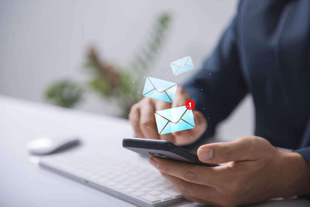 Email-рассылки помогают увеличить число регистраций и вовлечённость участников и продвигать вебинар Человек использует смартфон с уведомлениями по электронной почте символизируя email-маркетинг вебинара