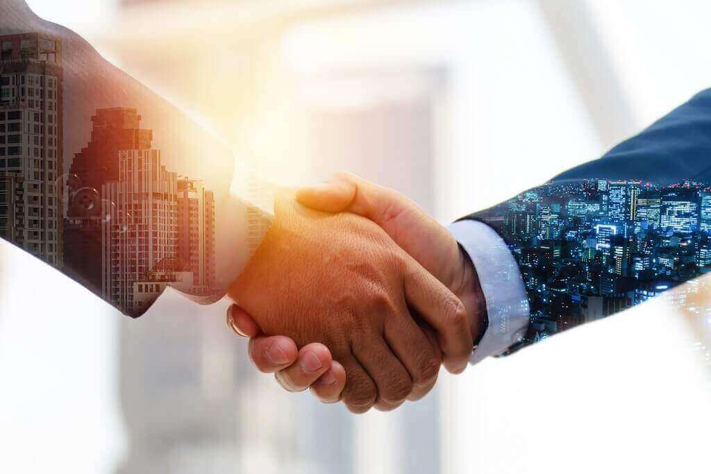 Рукостискання двох бізнес-партнерів на фоні міста символізує ефективне партнерство і взаємовигідну співпрацю